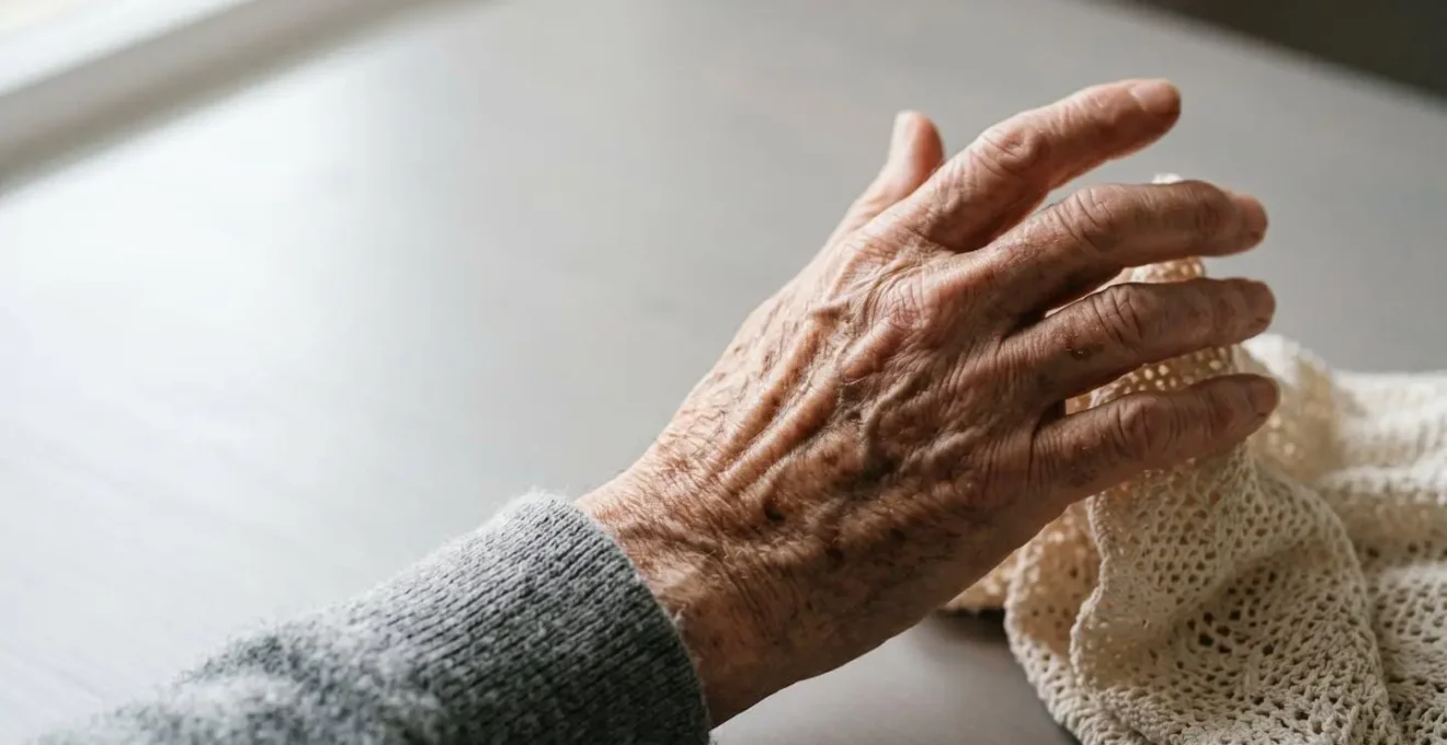 Close-up of an elderly person's hands struggling with a daily personal care task like dressing